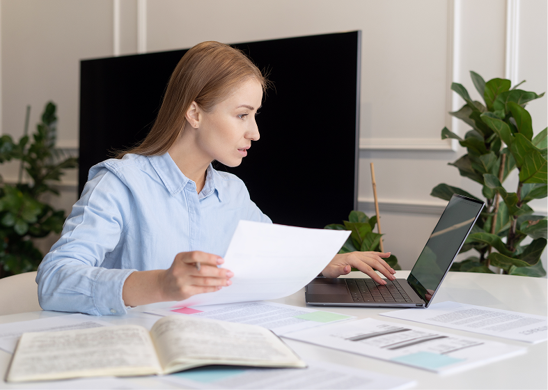 Woman working at laptop with documents